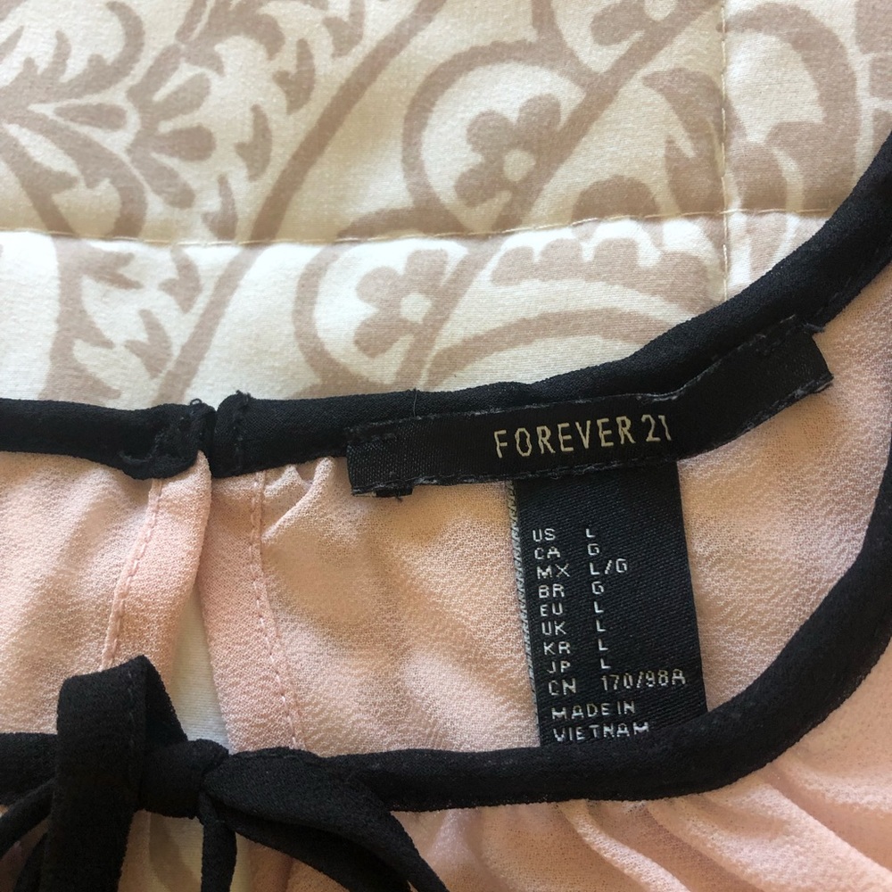 Peach colored blouse with black trim and ruffle sleeve.